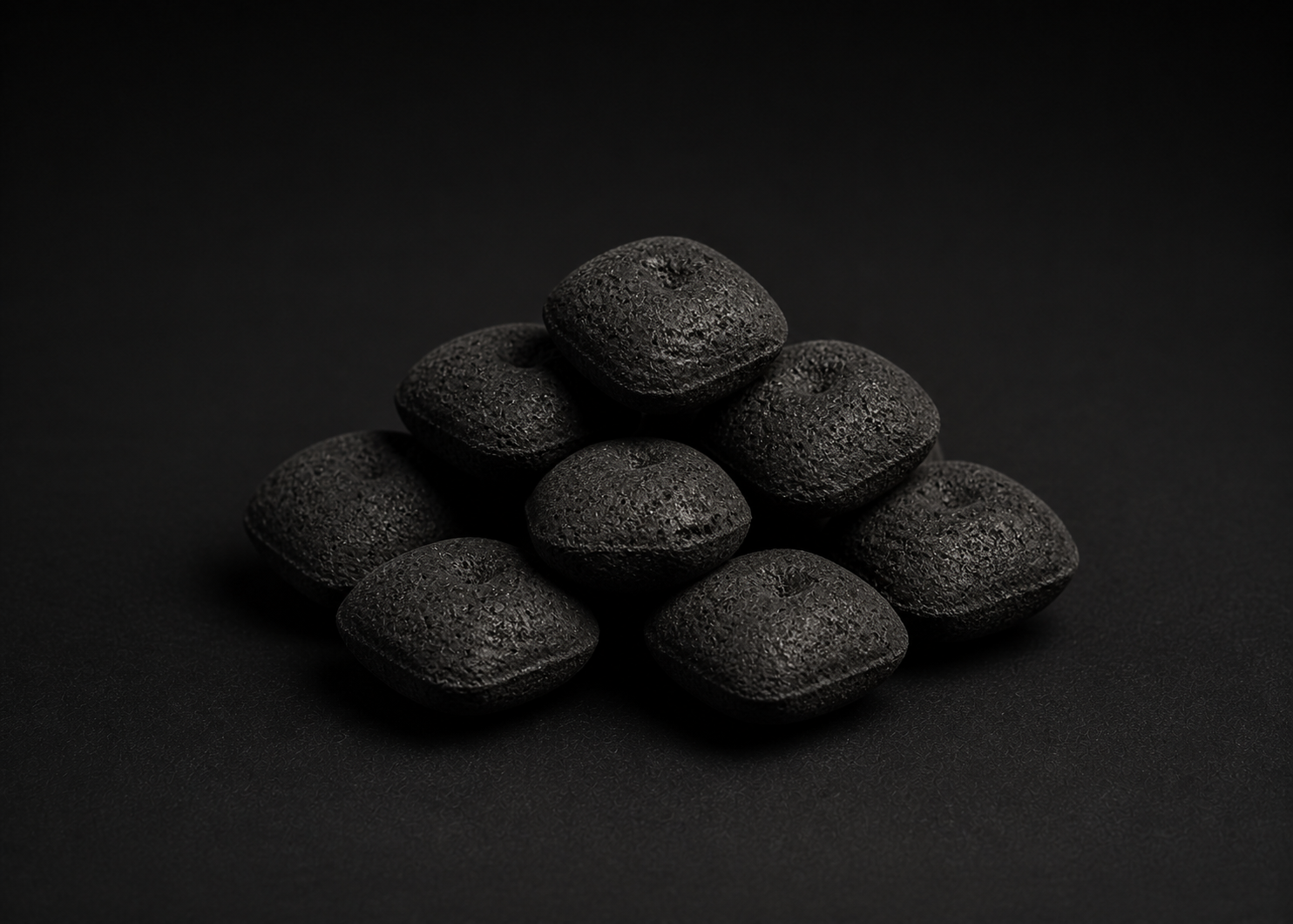 Illustrative group of unlit pillow-shaped BBQ charcoal briquettes
